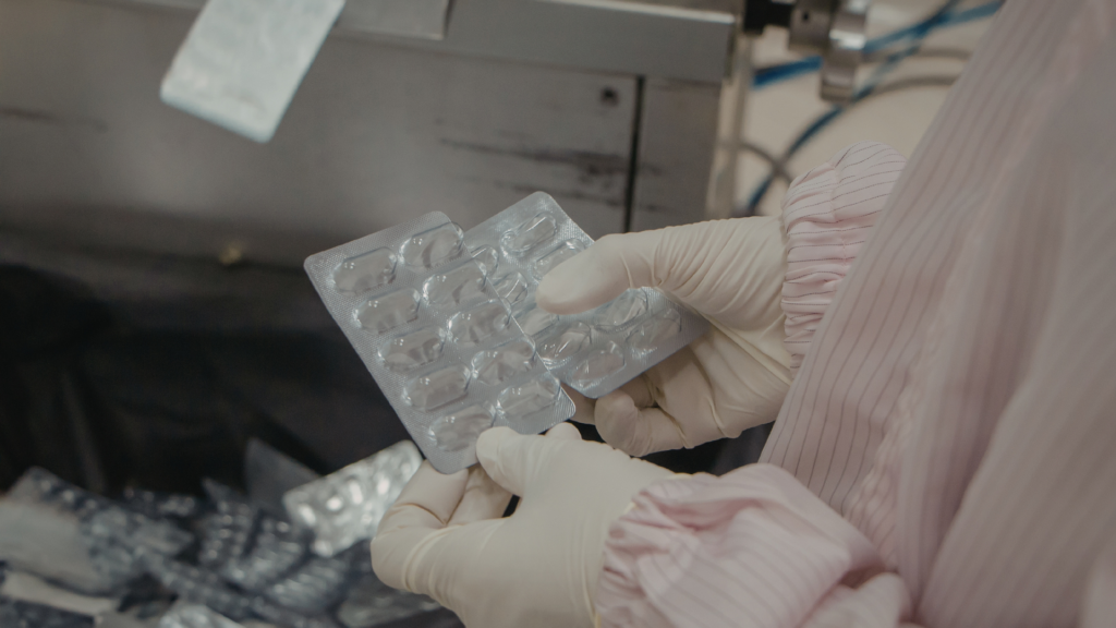 certificate-pharmaceutical-products-cpp-pharma-packaging Pharmaceutical worker inspecting blister packaging in a cleanroom facility for FDA-regulated pharmaceutical product manufacturing and export compliance