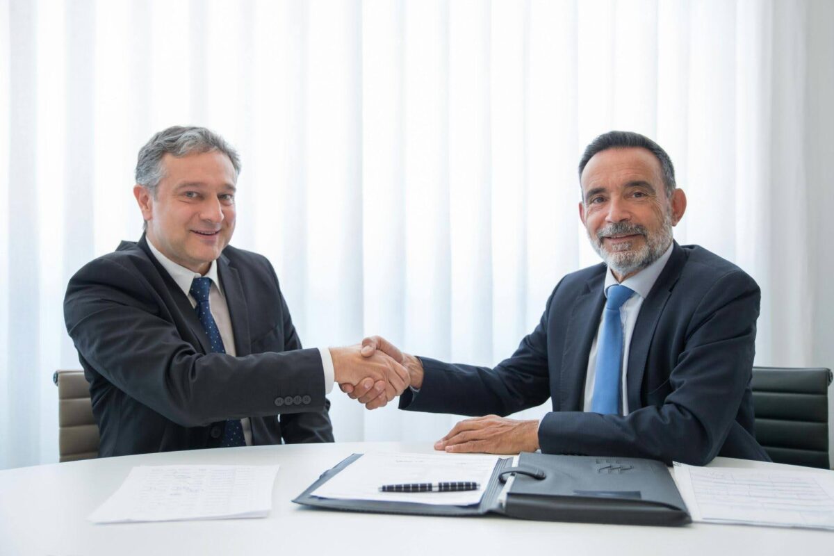 Business partners shaking hands after signing legal documents for apostille and embassy legalization services.